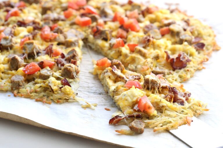 Breakfast pizza with a hash brown crust topped with eggs, bacon and tomatoes