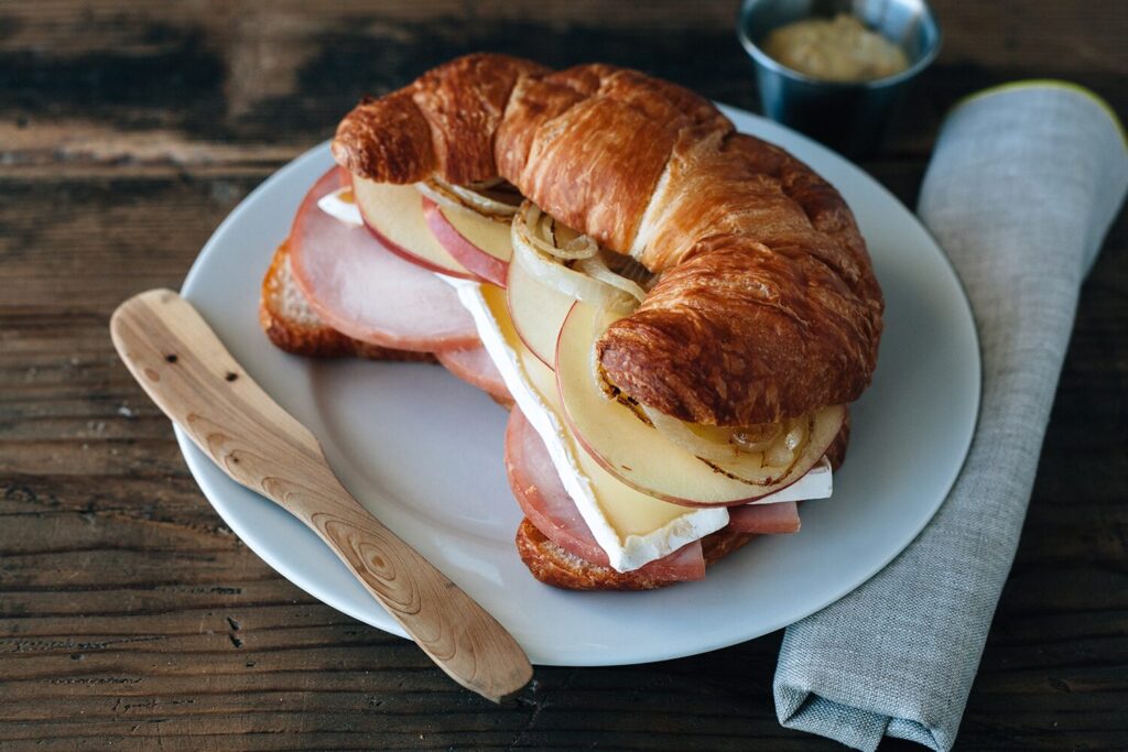 Croissant sandwich with ham, brie, and apple