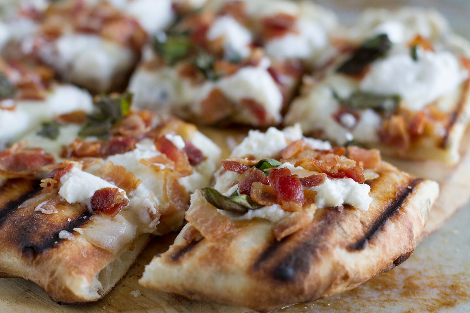 Grilled white pizza topped with bacon and basil