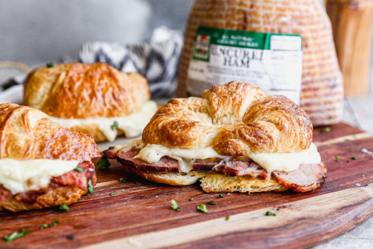 Three Croque Monsieur Croissant sandwiches with a Jones Dairy Farm Uncured Heritage Ham in the background.