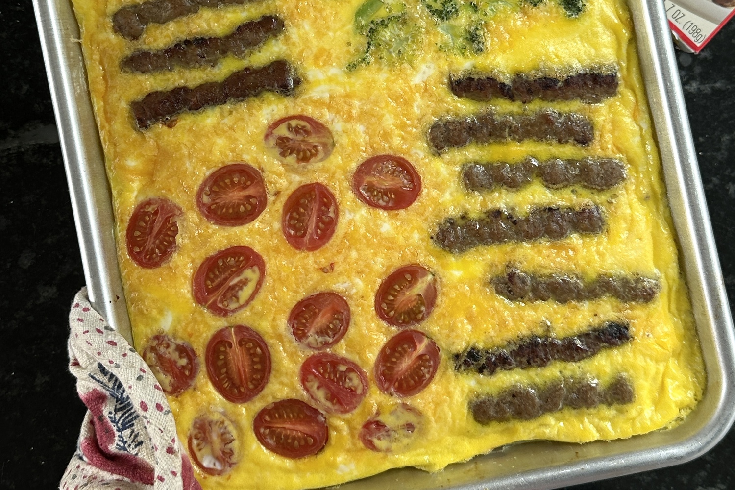 Eggs baked on a sheet pan with tomatoes and Jones Dairy Farm sausage.