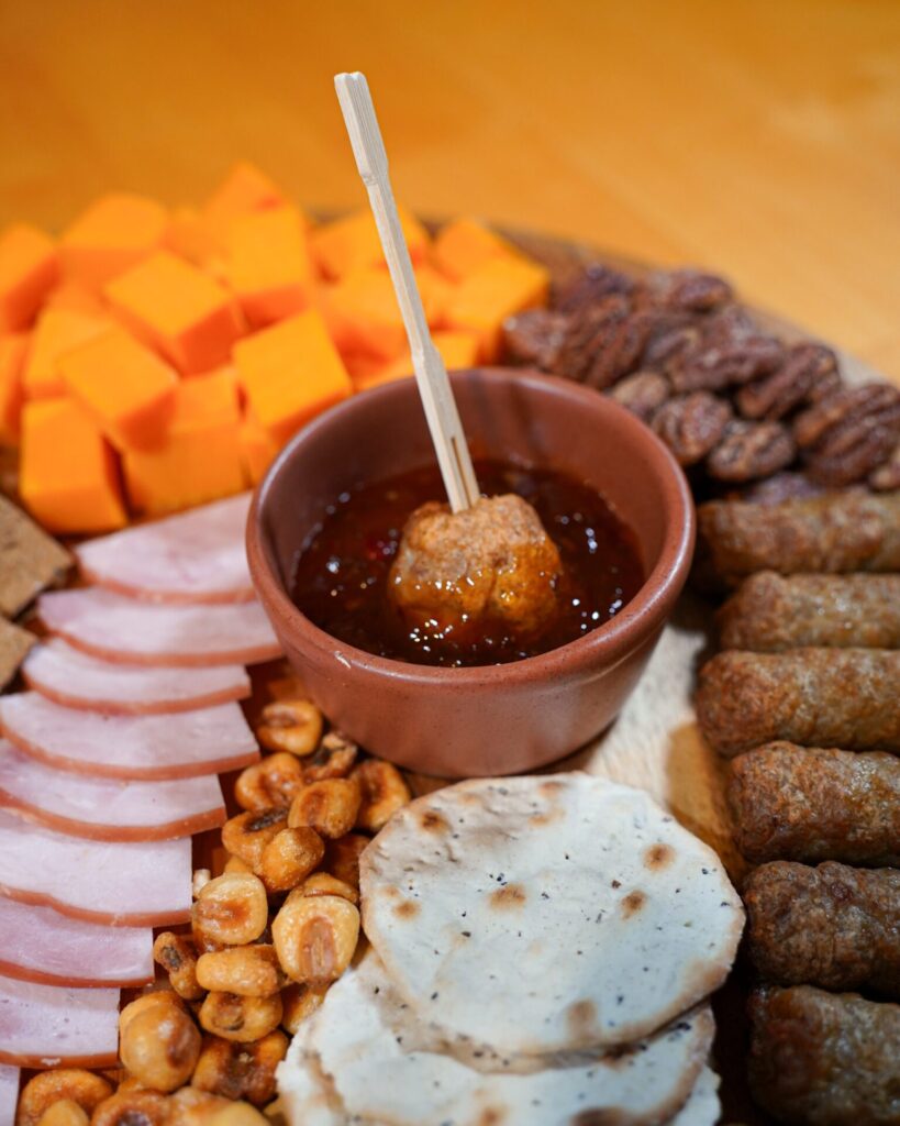 A pork meatball in hot pepper jelly on a charcuterie plate 