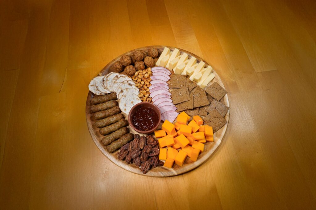 A cheese board featuring sausage, meatballs, and Canadian bacon