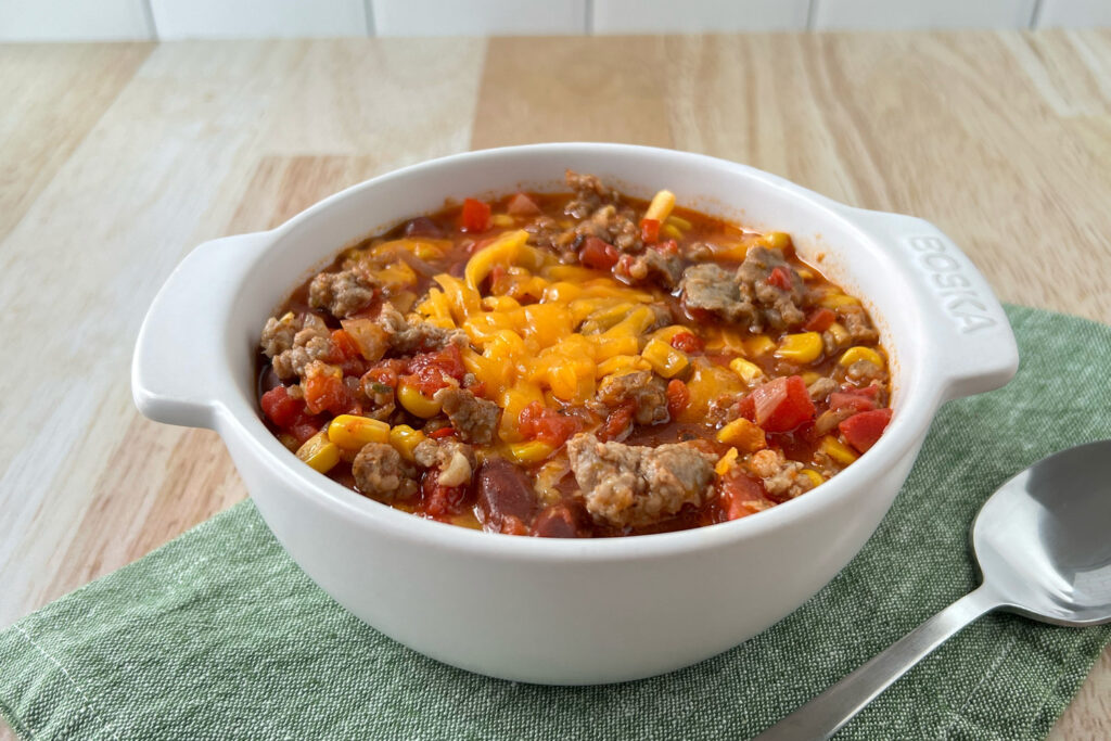 Sausage chili topped with cheddar cheese