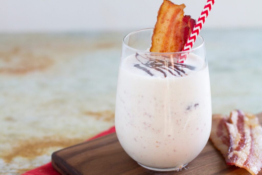 Vanilla milkshake topped with bacon and a chocolate drizzle